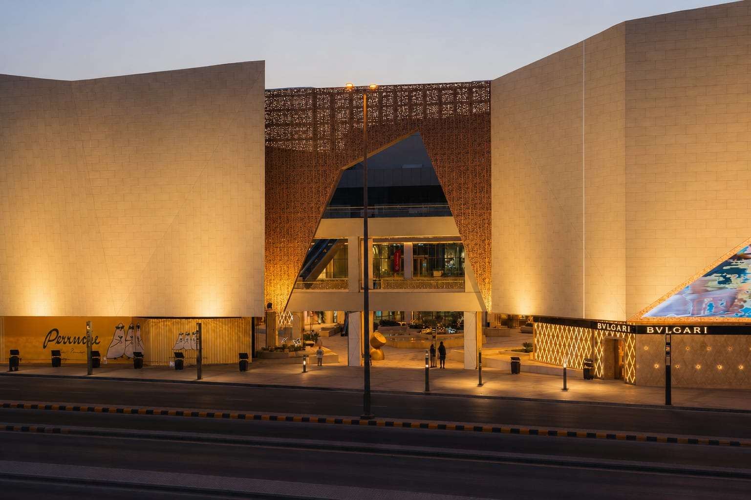 The main entrance of Solitaire Mall in Riyadh at dusk, its stone and latticework facade lit